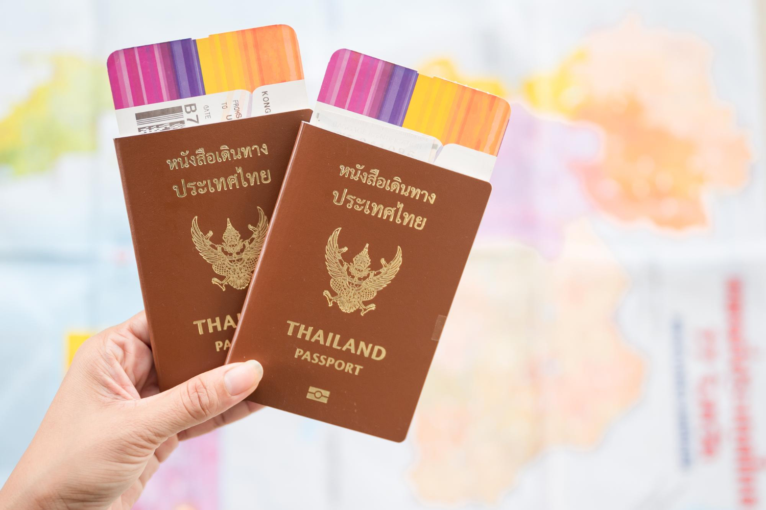 Two thai passport passports held in a hand.jpg